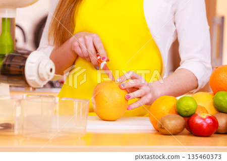 Woman housewife in kitchen cutting orange fruits 135460373