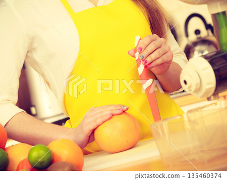 Woman in kitchen preparing fruits for juicing 135460374