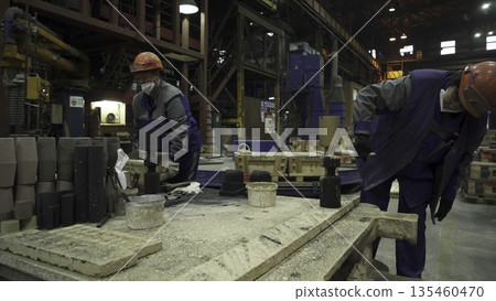 Foundry workers preparing molds for metal casting. Stock clip Foundry workers preparing molds for metal casting. Stock clip 135460470