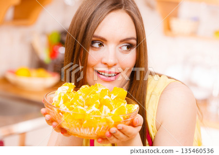 Woman holds bowl full of sliced orange fruits Woman holds bowl full of sliced orange fruits 135460536