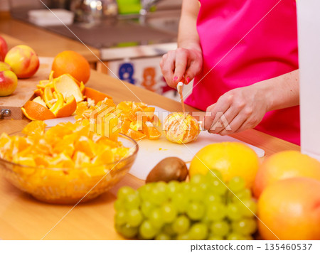 Woman housewife in kitchen cutting orange fruits 135460537
