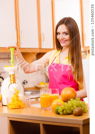 Woman making orange juice in juicer machine 135460539