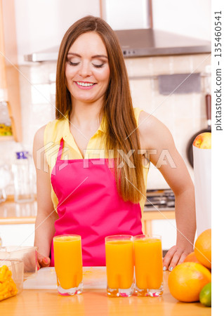 Woman in kitchen drinking fresh orange juice 135460541