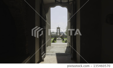 Revealing majestic italian garden and bell tower through villa entrance. Action 135460570