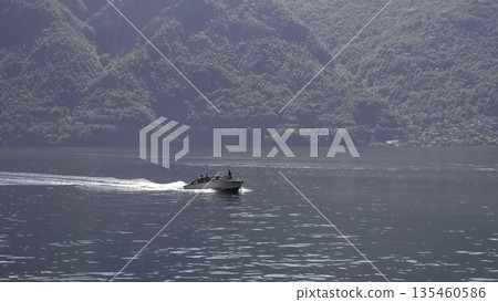 Enjoy a scenic boat ride on calm waters, surrounded by beautiful green mountains. Action Enjoy a scenic boat ride on calm waters, surrounded by beautiful green mountains. Action 135460586