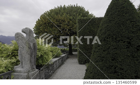 A Beautiful Garden Pathway adorned with a Stunning Sculpture and Lush Greenery all around. Action 135460599