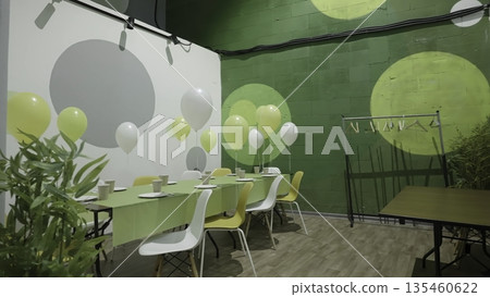 Festive table setting with balloons in green and white decorated room. Creative Festive table setting with balloons in green and white decorated room. Creative 135460622