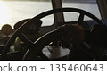 Captain steering ship wheel on bridge during golden hour. Clip 135460643