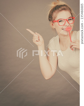Happy woman holding fake lips on stick Happy woman holding fake lips on stick 135460885