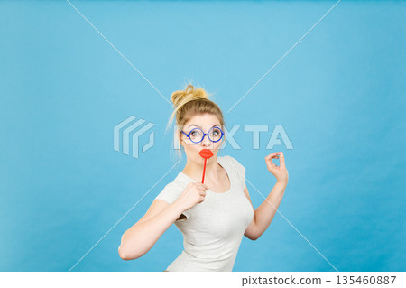 Happy woman holding fake lips on stick Happy woman holding fake lips on stick 135460887