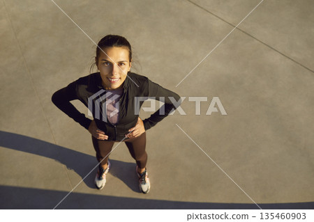 Confident young female runner resting outdoors after workout, hands on hips Confident young female runner resting outdoors after workout, hands on hips 135460903