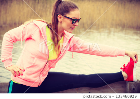Girl training in sporty clothes on lake shore Girl training in sporty clothes on lake shore 135460929