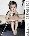 Vintage portrait of a little boy sitting at a table with toy cars. Funny photo of a cute boy. Retro photo from 1969. 135461494