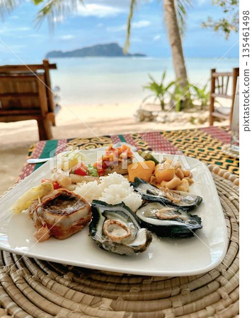 Gourmet seafood platter with oysters and rice served on a tropical beach resort 135461498