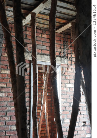 A house under construction. Brick interior walls, wooden supports and planks for metal slabs for pouring concrete ceiling, aluminum frame of the doorway. Brick house construction technology. 135461514