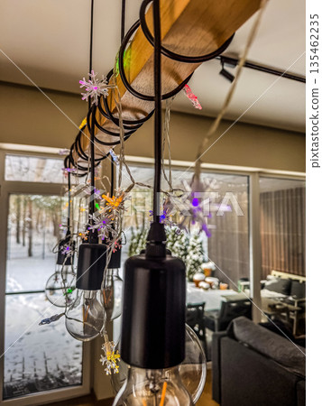 A close-up of a modern, industrial-style light fixture made of wood and metal, decorated for the holidays with colorful snowflake-shaped Christmas lights.. High quality photo A close-up of a modern, industrial-style light fixture made of wood and metal, decorated for the holidays with colorful snowflake-shaped Christmas lights.. High quality photo 135462235