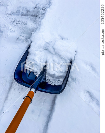 A first-person point-of-view shot of shoveling and clearing a path through heavy, wet snow. A necessary winter chore after a snowstorm.High quality photo 135462236