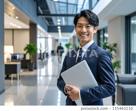 辦公室裡，一位商務人士站在電腦前。 135463210