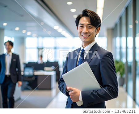 辦公室裡,一位商務人士站在電腦前。 辦公室裡,一位商務人士站在電腦前。 135463211