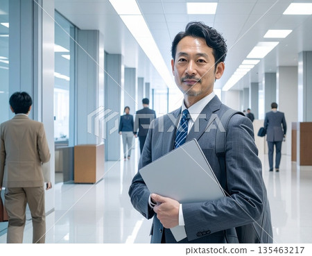 辦公室裡,一位商務人士站在電腦前。 辦公室裡,一位商務人士站在電腦前。 135463217