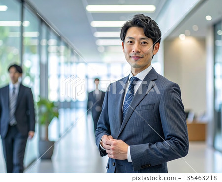 辦公室裡,一位商務人士站在電腦前。 辦公室裡,一位商務人士站在電腦前。 135463218