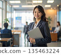 辦公室裡，一位商務人士站在電腦前。 135463224