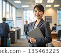 辦公室裡，一位商務人士站在電腦前。 135463225