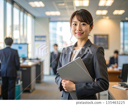 辦公室裡,一位商務人士站在電腦前。 辦公室裡,一位商務人士站在電腦前。 135463225