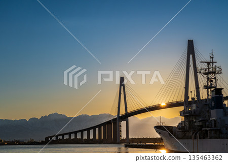 Shinminato Bridge and the Tateyama mountain range at dawn from Kaiwomaru Park Shinminato Bridge and the Tateyama mountain range at dawn from Kaiwomaru Park 135463362