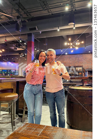A man and woman are posing for a picture in a bar A man and woman are posing for a picture in a bar 135463657
