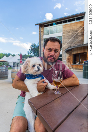 A man sits at a table with a dog on his lap A man sits at a table with a dog on his lap 135463660