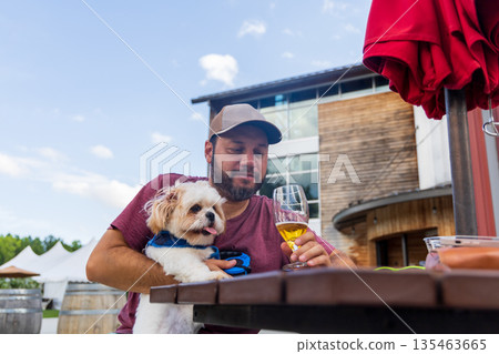 A man is sitting at a table with a dog on his lap 135463665