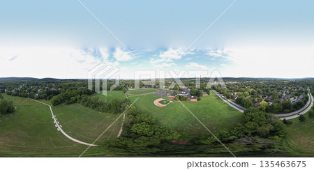 A panoramic view of a green field with a few houses in the background. Chesterbrook, USA 135463675