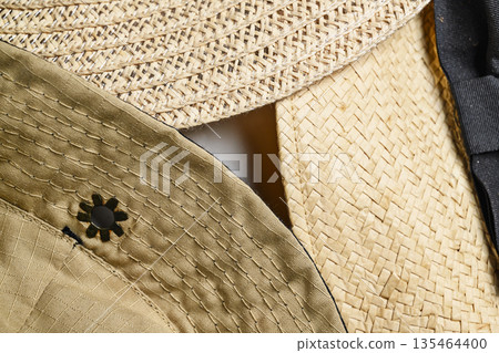 High-angle, macro shot showing the intricate details and textures of woven straw and khaki fabric hats, perfect for summer fashion and accessory backgrounds High-angle, macro shot showing the intricate details and textures of woven straw and khaki fabric hats, perfect for summer fashion and accessory backgrounds 135464400