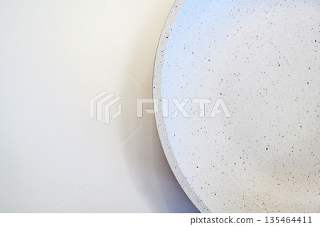 A top-down view of a modern white ceramic bowl with brown speckles, set against a clean off-white background. Perfect for minimalist food photography or lifestyle backgrounds 135464411