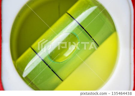 A macro view of a green spirit level vial. The air bubble is perfectly centered between the black marks, indicating a level surface for construction and DIY projects 135464438