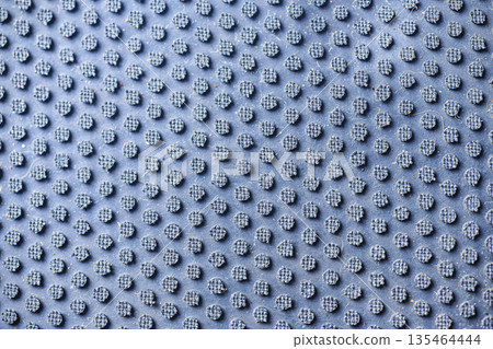 A detailed macro shot showing the textured surface of a blue table tennis paddle rubber with pips-out design, highlighting the intricate grid pattern and wear 135464444