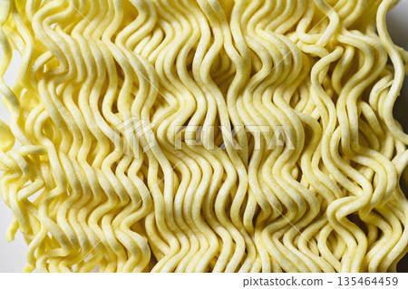 Detailed macro shot of dry wavy instant ramen noodles, showing the intricate texture and pale yellow color of uncooked pasta. Ideal for food and cooking themes Detailed macro shot of dry wavy instant ramen noodles, showing the intricate texture and pale yellow color of uncooked pasta. Ideal for food and cooking themes 135464459