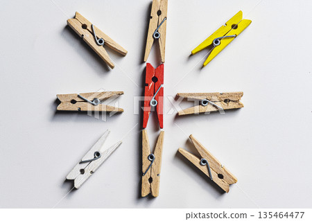 A red clothespin in the center of a circle made of wooden, yellow, and white clothespins, symbolizing leadership and uniqueness on a white background A red clothespin in the center of a circle made of wooden, yellow, and white clothespins, symbolizing leadership and uniqueness on a white background 135464477