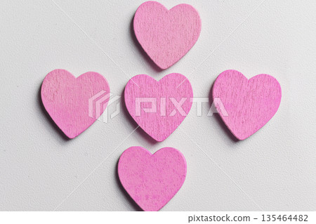 Five small pink wooden hearts arranged in a cross pattern on a white textured background. A minimal and romantic composition perfect for Valentine's Day, love, and greeting card designs Five small pink wooden hearts arranged in a cross pattern on a white textured background. A minimal and romantic composition perfect for Valentine's Day, love, and greeting card designs 135464482