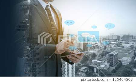 Professional businessman in a suit using a digital tablet for customer feedback, featuring speech bubble icons and a double exposure cityscape background for modern business concepts Professional businessman in a suit using a digital tablet for customer feedback, featuring speech bubble icons and a double exposure cityscape background for modern business concepts 135464503