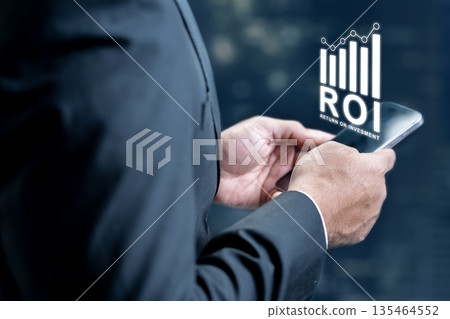 Professional in a suit using a smartphone to monitor return on investment. Digital bar chart ROI graphic overlay representing business growth, financial analytics, and profit tracking Professional in a suit using a smartphone to monitor return on investment. Digital bar chart ROI graphic overlay representing business growth, financial analytics, and profit tracking 135464552