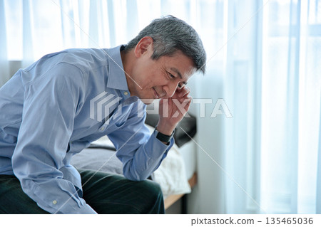 一位老人坐在床上,憂心忡忡。 一位老人坐在床上,憂心忡忡。 135465036