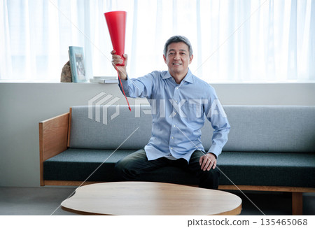 Senior man cheering while watching TV Senior man cheering while watching TV 135465068