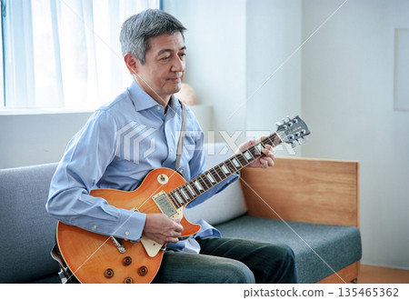 Smiling senior man holding an electric guitar Smiling senior man holding an electric guitar 135465362