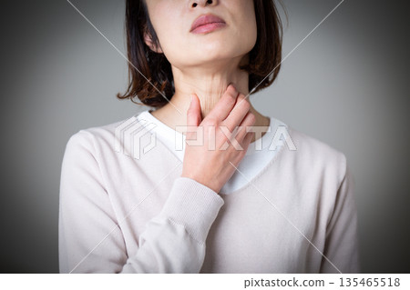 A middle-aged woman suffering while holding her throat 135465518