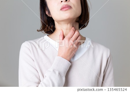 A middle-aged woman suffering while holding her throat 135465524