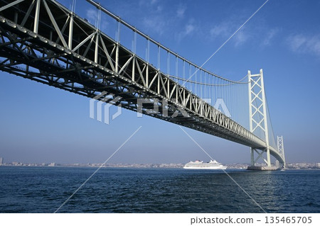 Distant view of a cruise ship passing through the Akashi Kaikyo Bridge 135465705