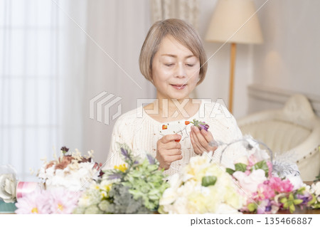 一位老婦人在客廳以插花為樂 一位老婦人在客廳以插花為樂 135466887