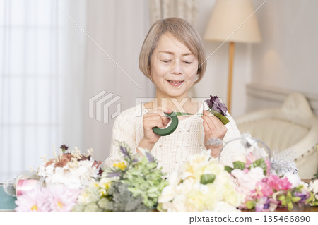 Senior woman arranging flowers as a hobby in the living room 135466890